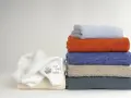 Ammorbidente asciugamani: una pila di asciugamani colorati e un morbido asciugamano bianco con un disegno per bambini.