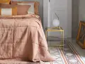 Un morbido quilt matrimoniale color pesca, con cuciture a quadri, adorna un letto in una stanza elegante.