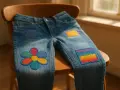 Jeans con vivaci rammendi creativi: un fiore colorato e un arcobaleno, che trasformano un capo semplice in un'opera d'arte.