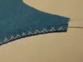 Bordo di feltro blu rifinito con un punto overlock a mano.