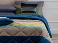 Trapunta a righe colorate, con cuscini coordinati. Perfetta per capire se è più calda la trapunta o il piumino.