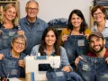 Un gruppo sorridente mostra i loro jeans con toppe decorative, un esempio di rammendo jeans a mano.