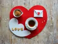 Tovagliette colazione fai da te a forma di cuore, con biscotti, tè e una busta decorata.