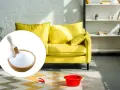 A bowl of baking soda with a scoop, next to a yellow sofa and cleaning supplies.