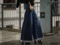 Woman wearing wide-leg denim palazzo pants with frayed hems and platform sandals.