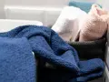 Asciugamani spugna blu, bianchi, rosa e azzurri in un cesto. Il primo lavaggio li rende ancora più soffici e pronti all'uso.