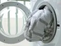 A white and grey checkered duvet being loaded into a washing machine.