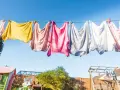Panni colorati stesi al sole su un filo, un'immagine di vita quotidiana e la gioia di stendere i panni all'aria aperta.