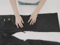 Mani che preparano un buco nei pantaloni neri per rammendare.
