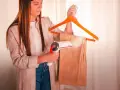 Donna usa un vaporizzatore per stirare velocemente i pantaloni appesi a una gruccia.