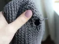 Dito un buco in un maglione grigio, pronto per imparare come rammendare uno strappo a mano.