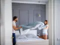 Coppia felice che cambia le lenzuola, un gesto che ci ricorda ogni quanto cambiare le lenzuola per un sonno più sano.