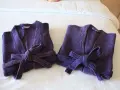 Due accappatoi viola, piegati e legati con la loro cintura, pronti per essere riposti. Ecco come piegare un accappatoio per un riordino perfetto.