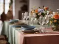 Tavola apparecchiata con piatti blu e beige, bicchieri e fiori colorati. Un esempio di come abbinare i piatti alla tovaglia sfumata.