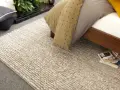 Un grande tappeto di lana intrecciata accanto a un letto. Scopri come lavare un tappeto di lana grande per mantenerlo come nuovo.