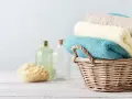 Cesto di vimini con asciugamani morbidi, come i rimedi della nonna. Accanto, spugna naturale e bottiglie di vetro.