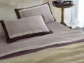 Letti preparati con lenzuola in cotone percalle si stira, con federe lilla e bordi viola.