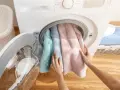Mani inseriscono asciugamani color pastello nella centrifuga asciugamani.