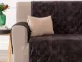 Divano con copridivano trapuntato marrone scuro, un cuscino beige e un vaso di fiori. Il miglior tessuto per divani per un look accogliente.