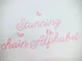 Punto ricamo per scritte: "Stunning chain Alphabet" in rosa, con piccole farfalle applicate.