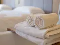 Asciugamani bianchi piegati e arrotolati, pronti per l'uso. Le misure asciugamani sono perfette per un bagno accogliente.
