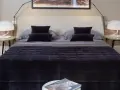 Un letto impeccabile, con copriletto trapuntato scuro e cuscini coordinati, mostra come rifare il letto in modo elegante.