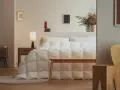 Un letto accogliente con un piumone bianco trapuntato, pronto per accogliere la parte tonda del piumone dove va, creando un nido perfetto.