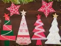 Alberi di Natale fai da te in stoffa, decorati con pizzi e stelle, creano un'atmosfera festiva e artigianale.