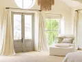 Tipi di bastoni per tende: un'elegante stanza con tende color crema che scendono da sottili aste metalliche, creando un'atmosfera accogliente.