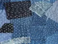 Tessuto patchwork in denim con cuciture bianche a punto croce e a zig-zag, un esempio di rammendo giapponese.