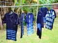 Abiti con motivi tie-dye blu e bianchi, pronti per asciugare dopo aver provato a tingere tessuti sintetici.
