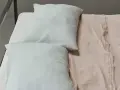 Due federe bianche su un lenzuolo color pesca. La morbidezza suggerisce lenzuola mano seta, un tocco di lusso per il riposo.