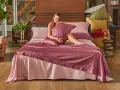 Donna sorridente su un letto con lenzuola rosa. Scopri come lavare le lenzuola nuove per mantenerle morbide e fresche.