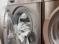 Lavatrice con un tappeto grigio all'interno, pronta per il lavaggio. Scopri come lavare i tappeti in lavatrice per mantenerli freschi e puliti.