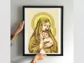 Cross-stitch of Madonna and Child in a black frame, held by hands.