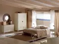 Camera da letto con letto tortora, armadio bianco e cassettiera. Abbinamenti eleganti per un ambiente rilassante con vista mare.
