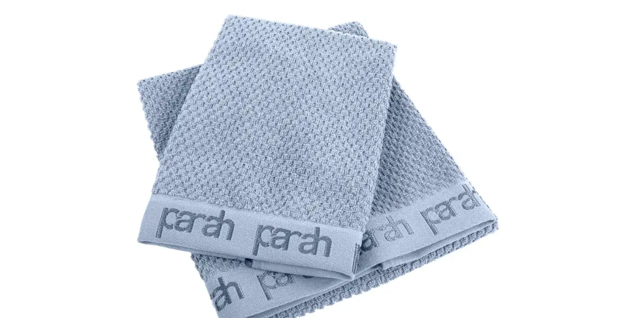 Due asciugamani azzurri con logo "parah" sovrapposti. Sembrano morbidi, ma chissà se sono asciugamani che non asciugano.