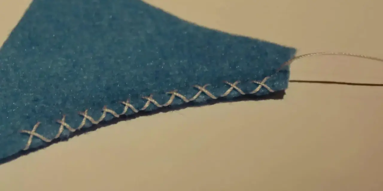 Bordo di feltro blu rifinito con un punto overlock a mano.