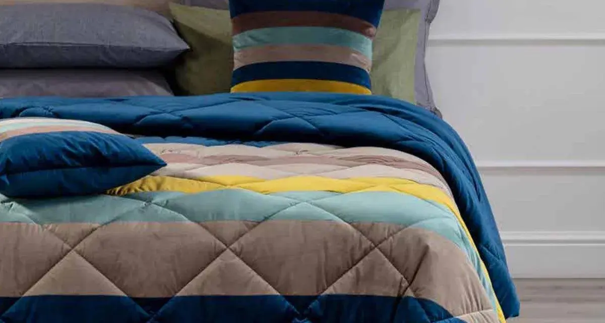 Trapunta a righe colorate, con cuscini coordinati. Perfetta per capire se è più calda la trapunta o il piumino.