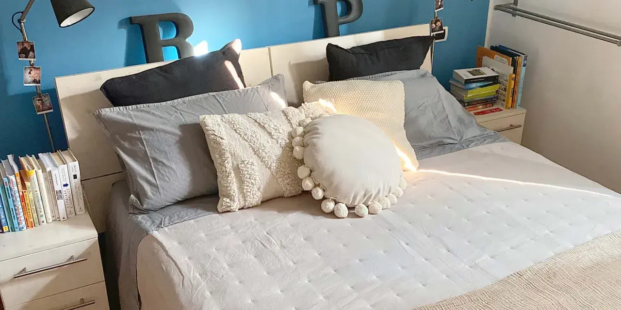 Letto con cuscini morbidi e coperta beige. Impara come fare il letto per un risveglio sereno.