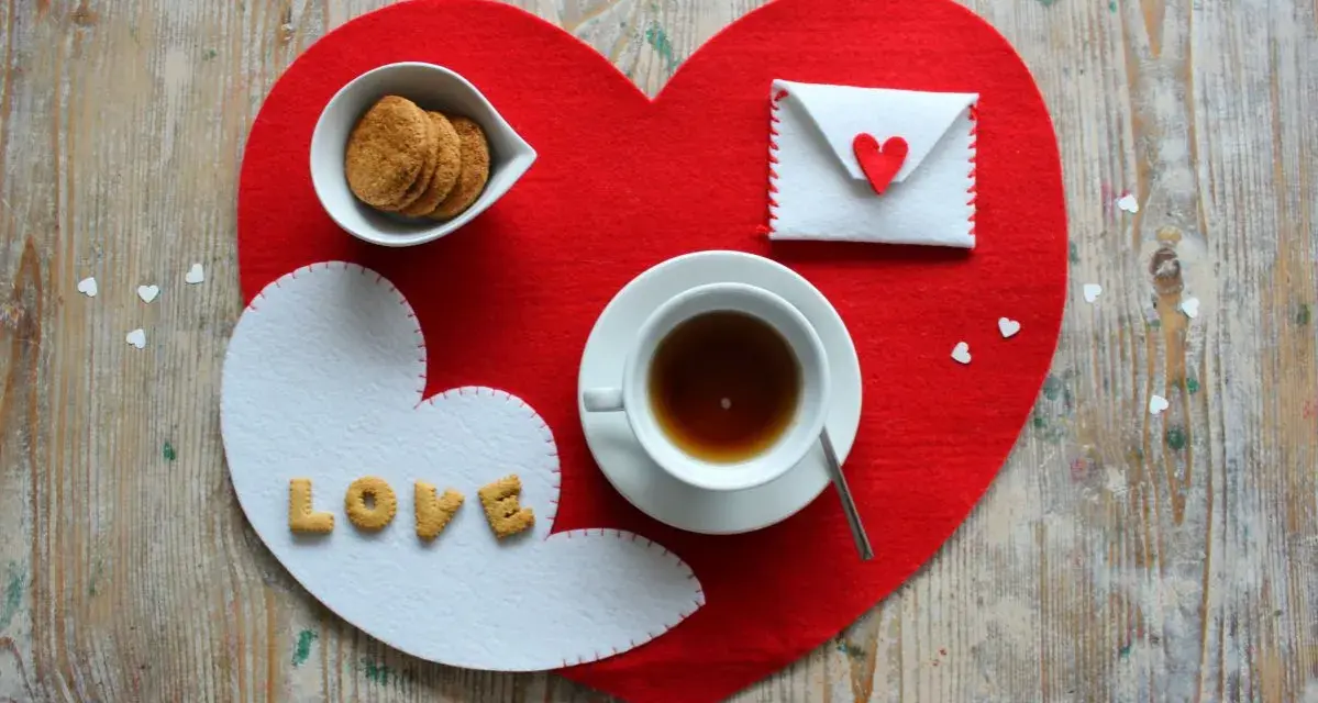 Tovagliette colazione fai da te a forma di cuore, con biscotti, tè e una busta decorata.