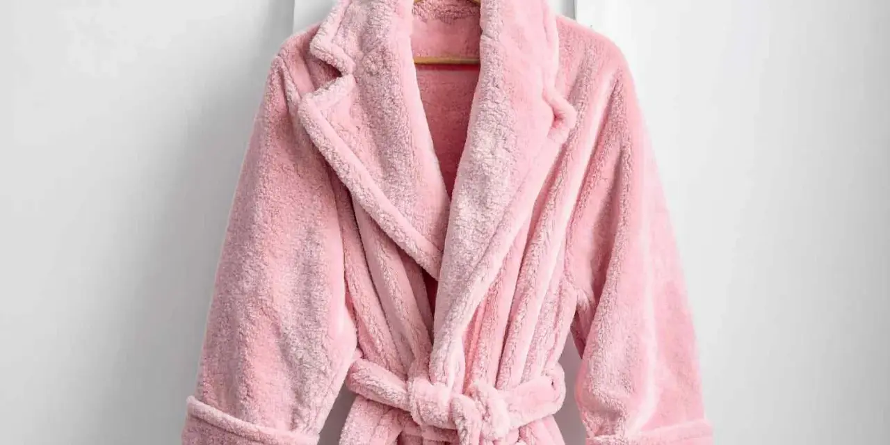 Accappatoio rosa soffice appeso. Scopri come lavare accappatoio in lavatrice per mantenerlo morbido e profumato.