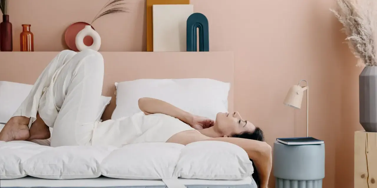 Donna rilassata su un letto con topper matrimoniale, che ne dimostra il comfort.
