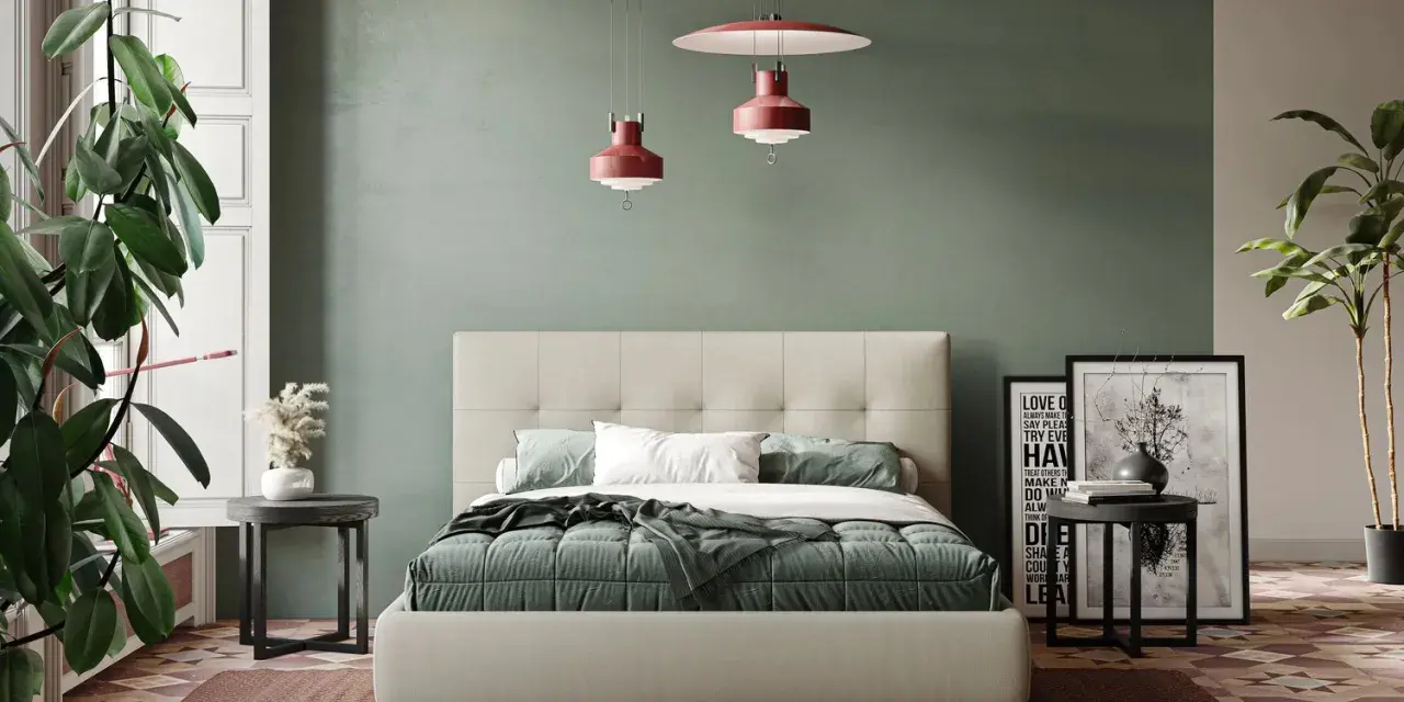 Letto moderno con testiera capitonné, copriletto verde e cuscini bianchi. Parti del letto ben visibili, con comodini e piante.