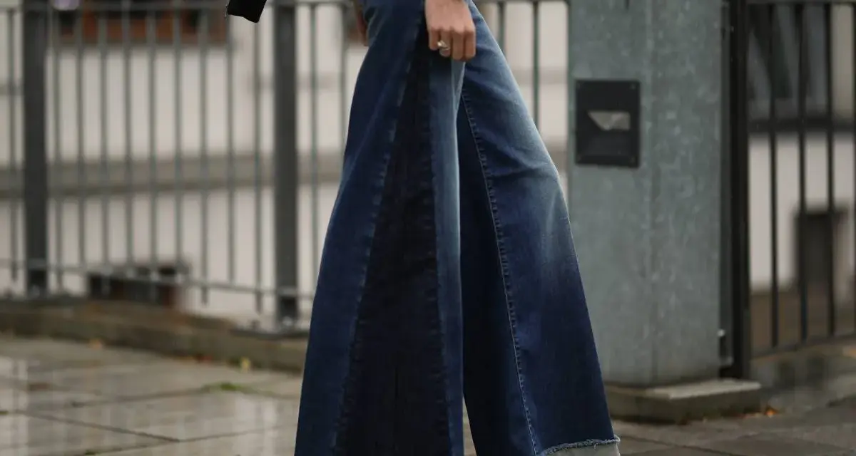 Woman wearing wide-leg denim palazzo pants with frayed hems and platform sandals.