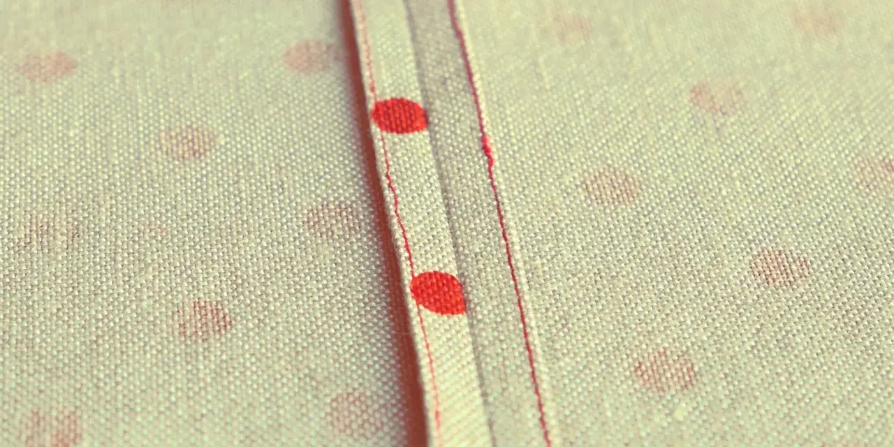 Tessuto a pois rossi con cucitura a vista, un punto per rifinire bordi con precisione sartoriale.