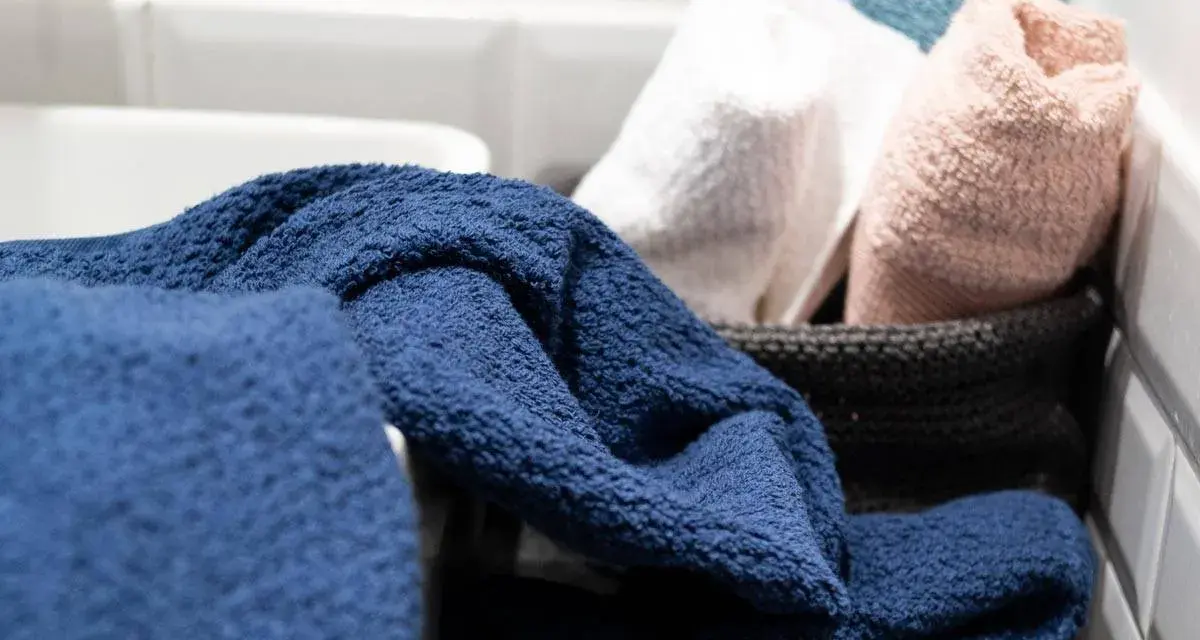 Asciugamani spugna blu, bianchi, rosa e azzurri in un cesto. Il primo lavaggio li rende ancora più soffici e pronti all'uso.