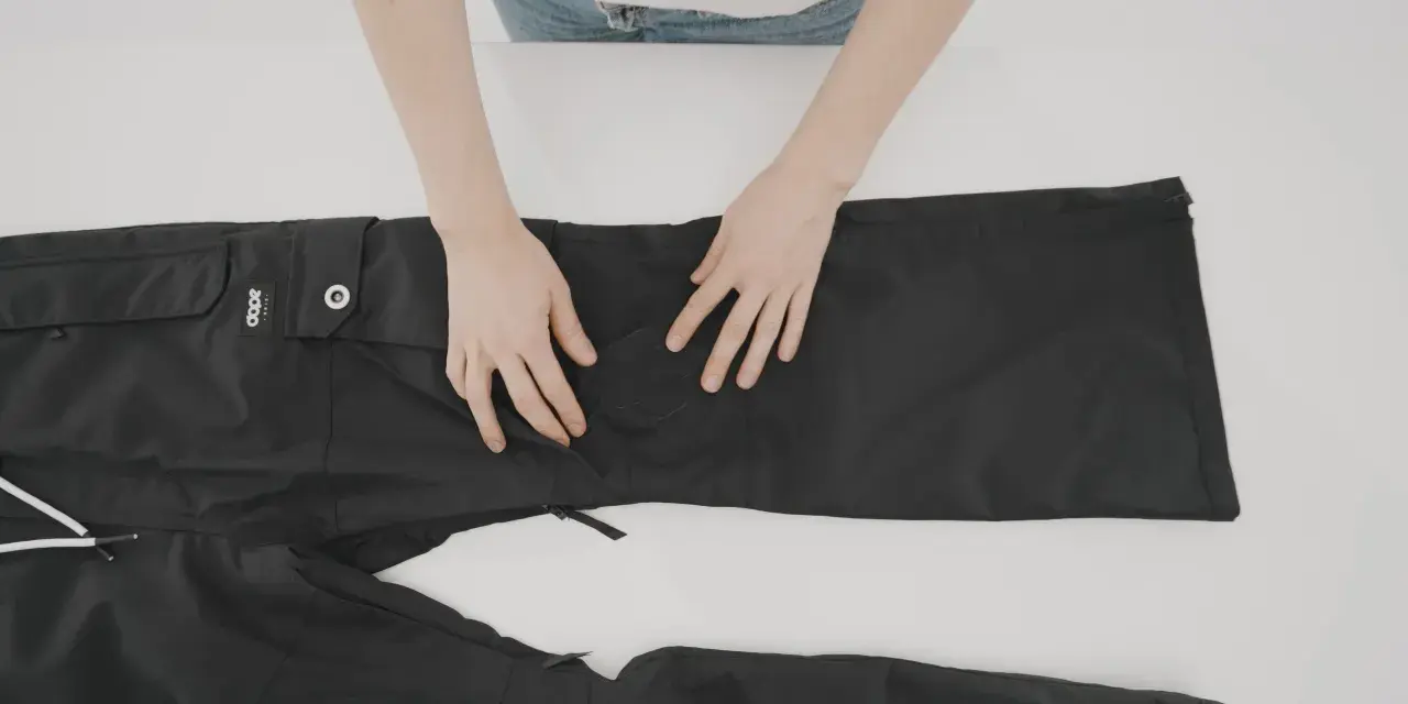 Mani che preparano un buco nei pantaloni neri per rammendare.