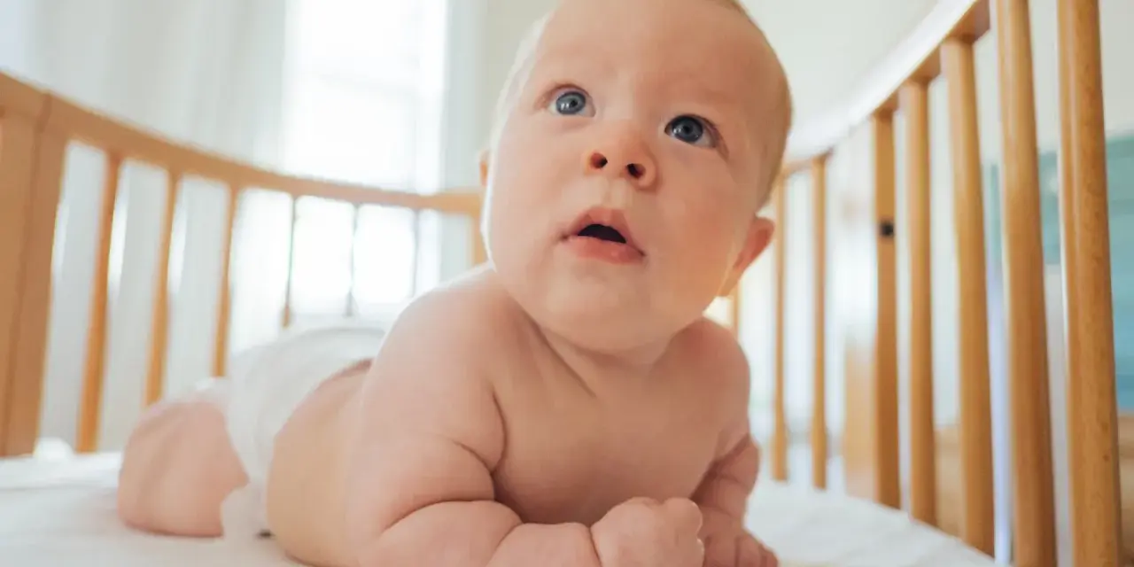 Bambino in culla, con pannolino, che esplora il mondo. Le misure lenzuolino culla sono perfette per questo piccolo esploratore.