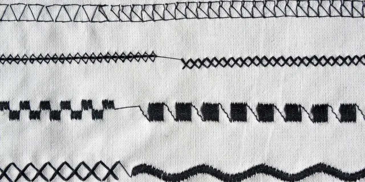 Close-up of various black sewing machine stitches on white fabric.